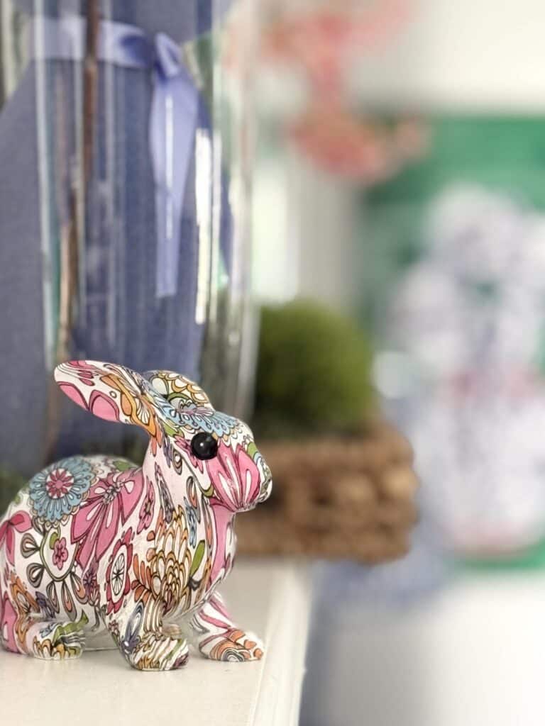 A colorful decor rabbit on a fireplace mantel.