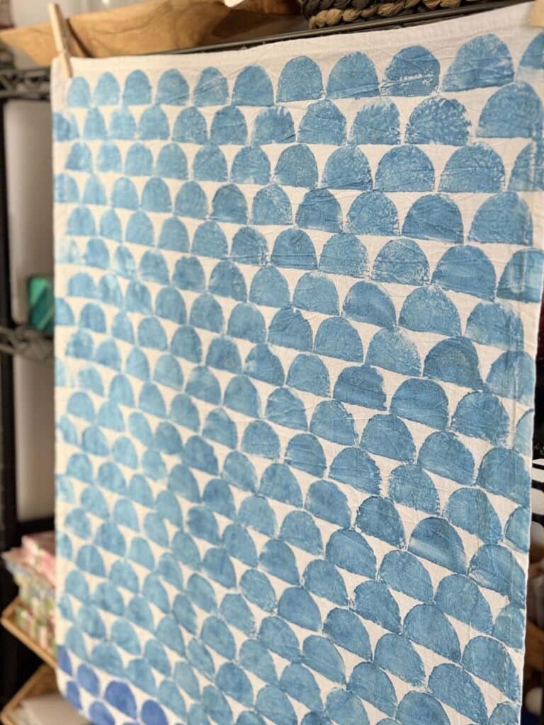 A tea towel with blue half moon pattern block printed on it.