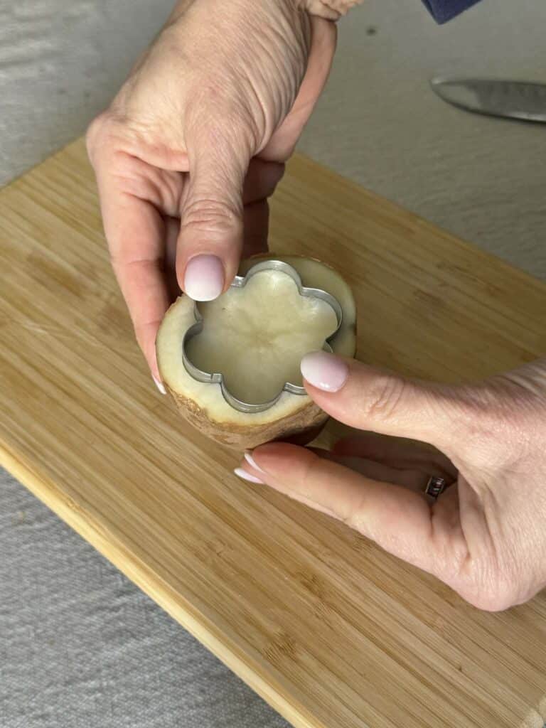 Pressing a cookie cutter into a potato for printing.