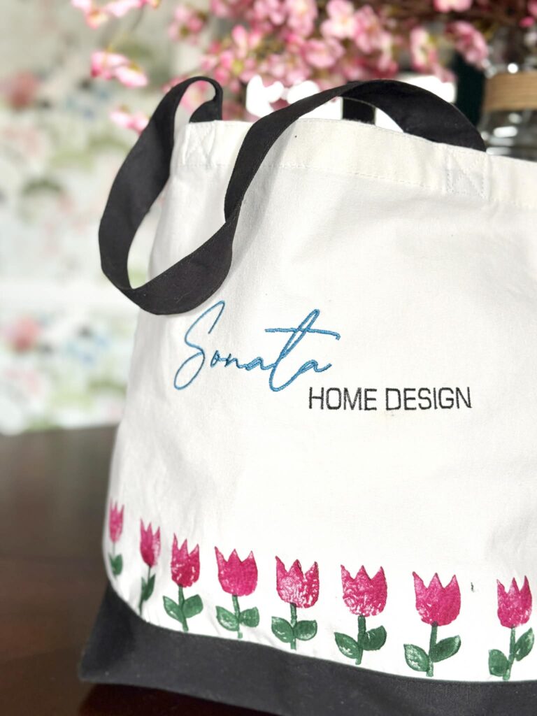 A tote bag that says Sonata Home Design and has block printed tulips on the bottom.