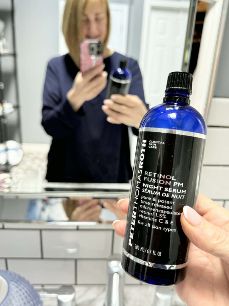 A woman holding a bottle of the Peter Thomas Roth retinol night serum as sold on QVC.