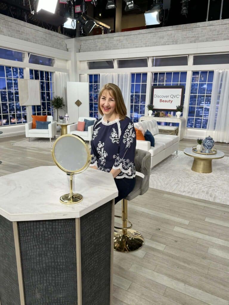 A woman sitting on the QVC set.