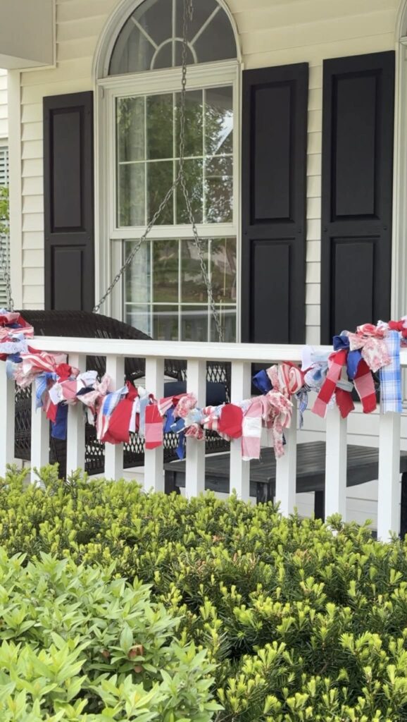 A fabric garland swag on a front porch railing.