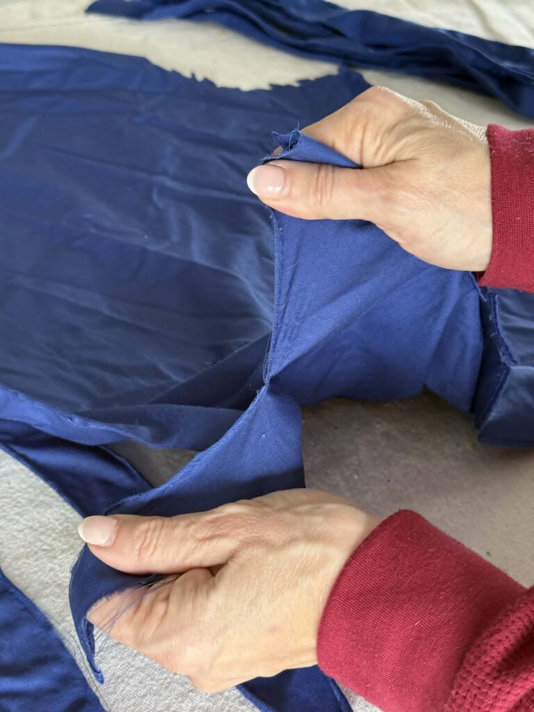 A woman's hands tearing a piece of blue fabric.