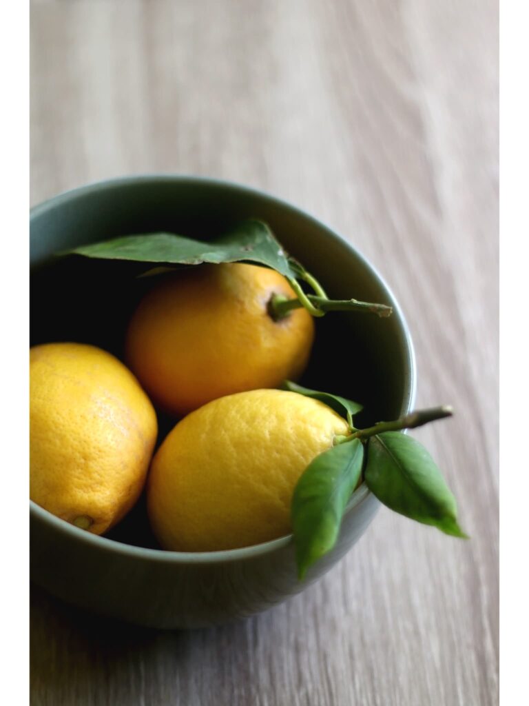 lemon kitchen decor ideas that include several lemons grouped in a green bowl.