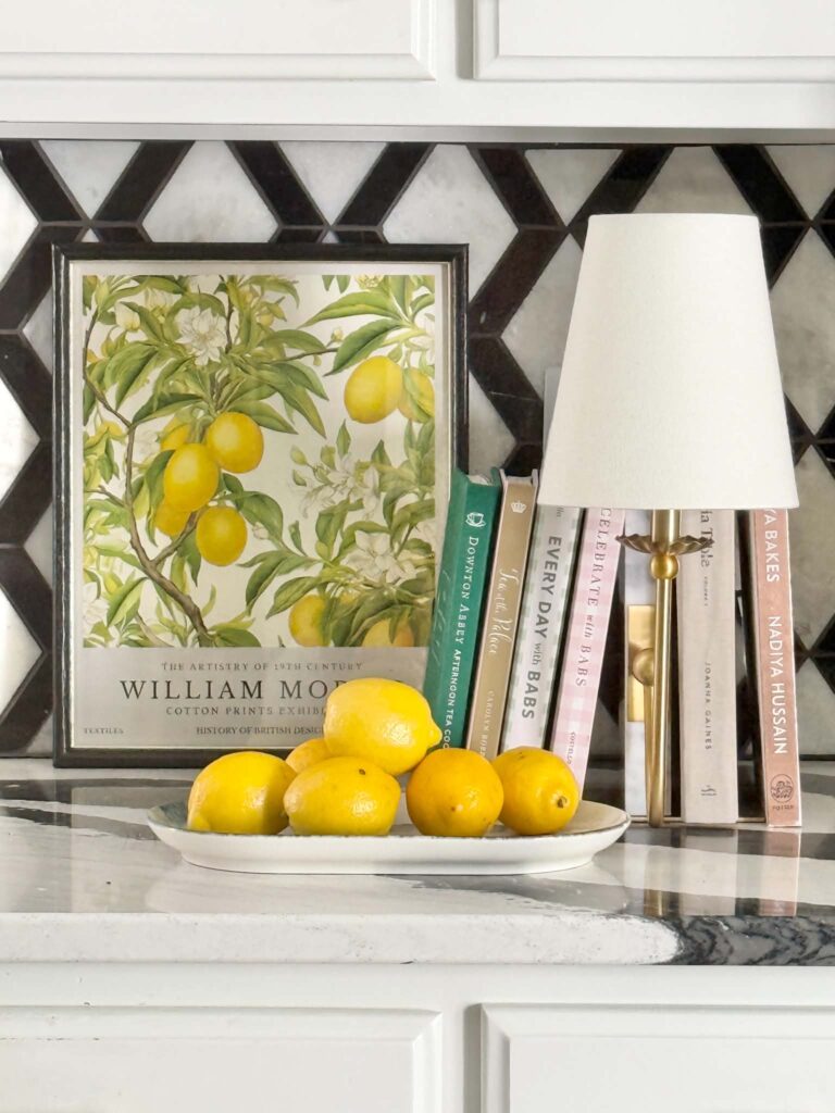 A Williams Morris lemon art print propped against a kitchen backsplash.
