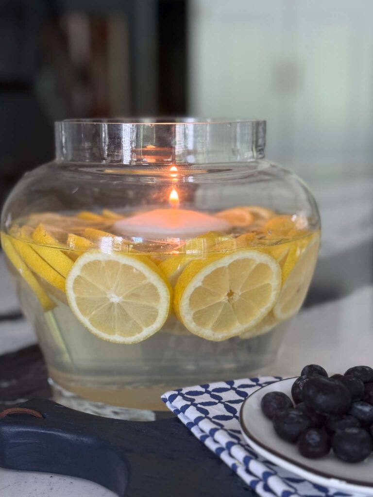 A glass vase filled with sliced lemons and a floating candle.
