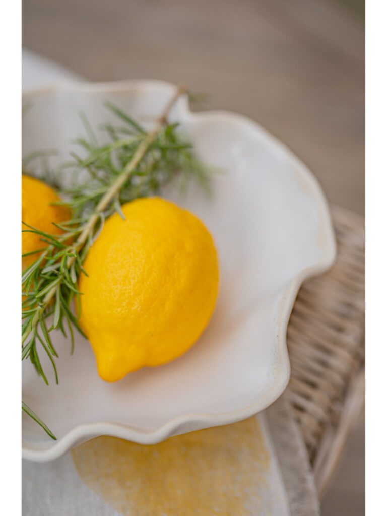 A yellow lemon in a white ceramic dish sitting on a kitchen counter.