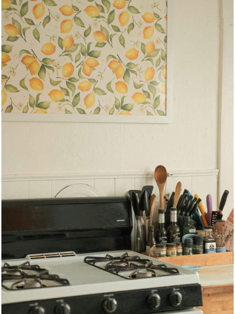 A framed piece of lemon wallpaper hanging about a kitchen stove.