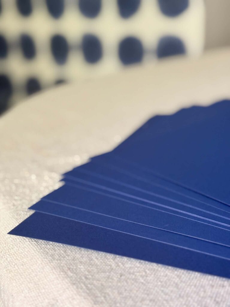 Navy blue card stock fanned out on a table.