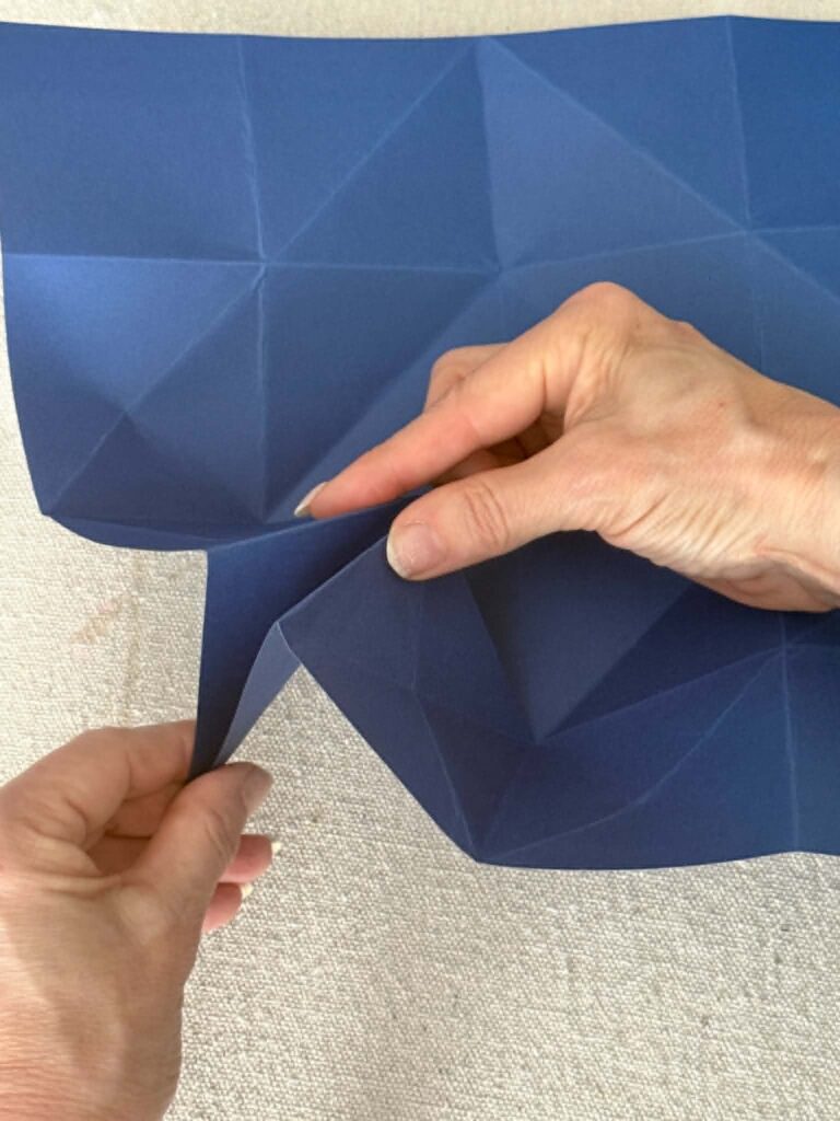 Folding the corner of a piece of thick paper to create an origami fold for an envelope.