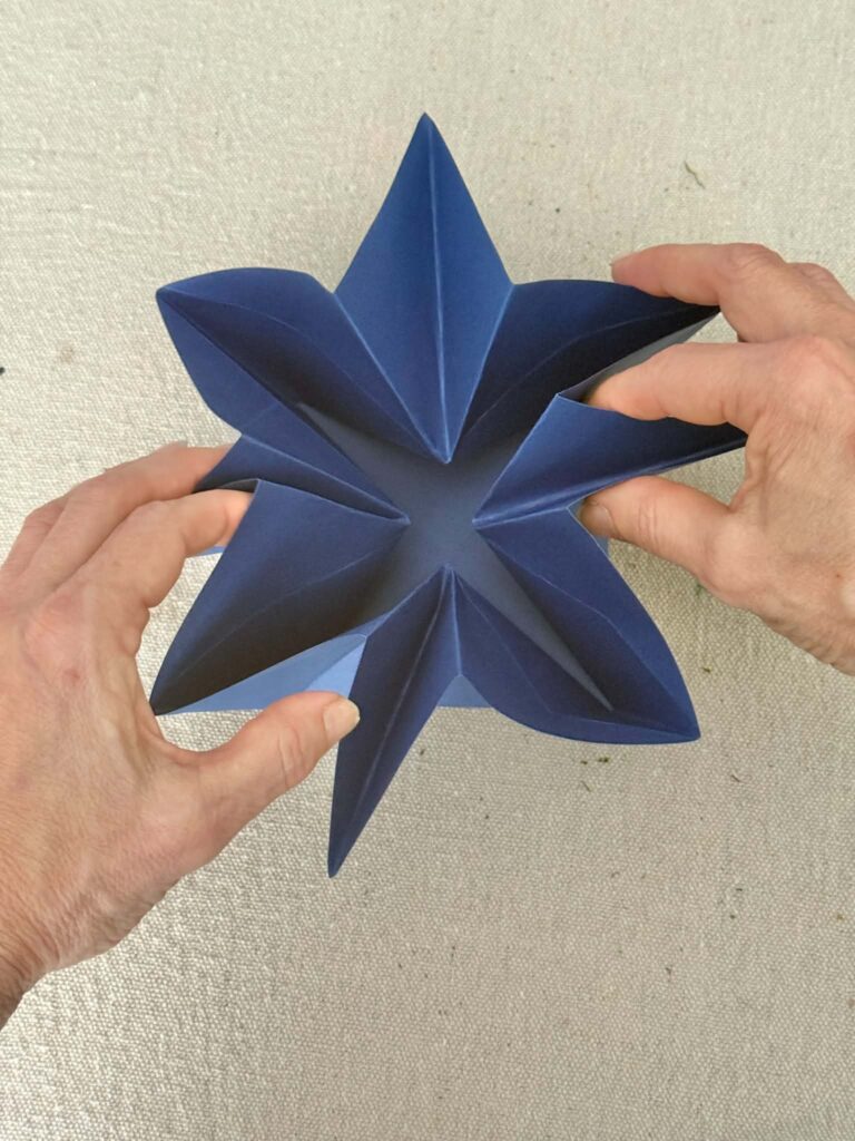 Pressing origami folds in toward the center to create an envelope.