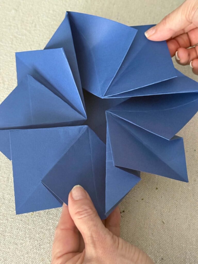 Folding an origami envelope inward to close the center hole.