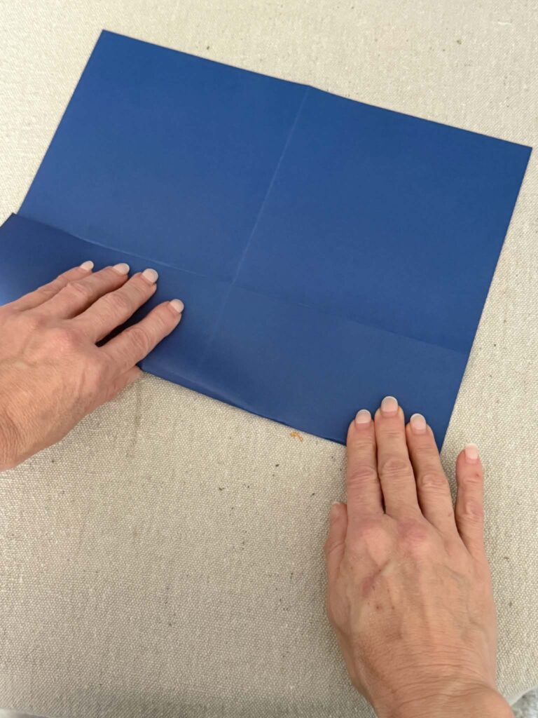 Folding the edges of card stock paper to create an envelope.