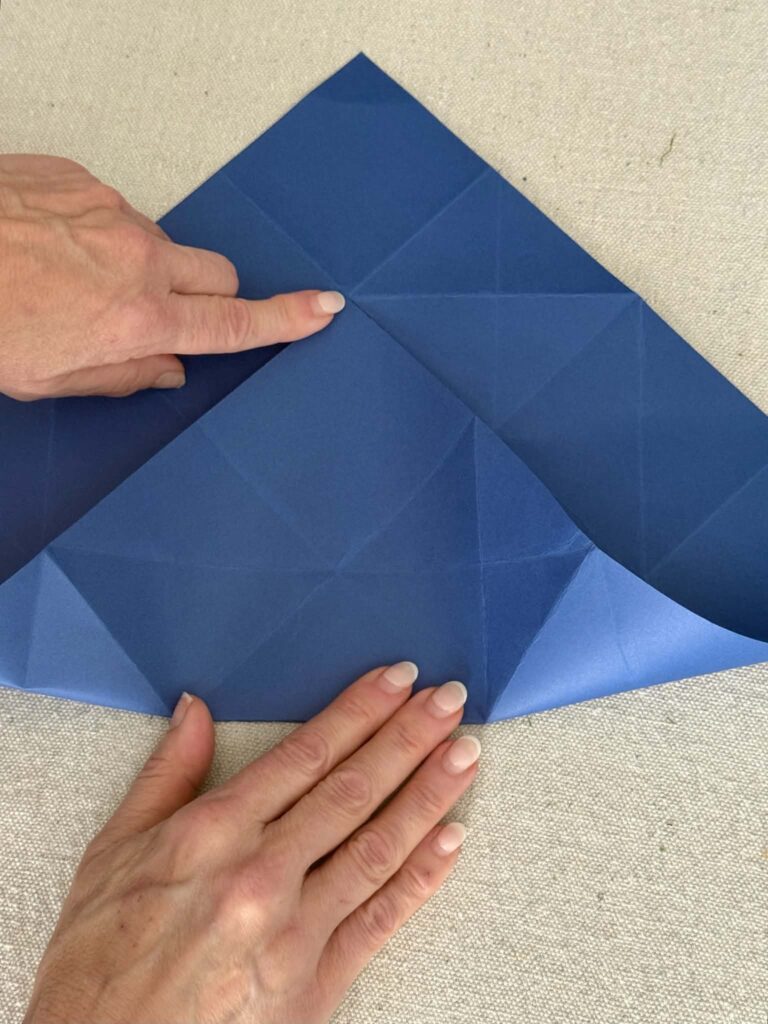 A two-thirds triangular fold in blue card stock paper for an origami envelope.