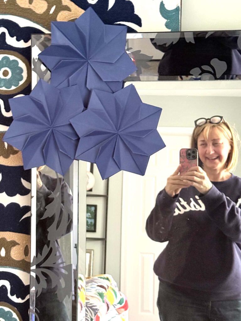 Origami flowers decorating the corner of a mirror.