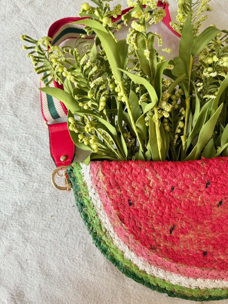 Faux greenery tucked into the top pocket of a diy door hanger that looks like a watermelon slice.