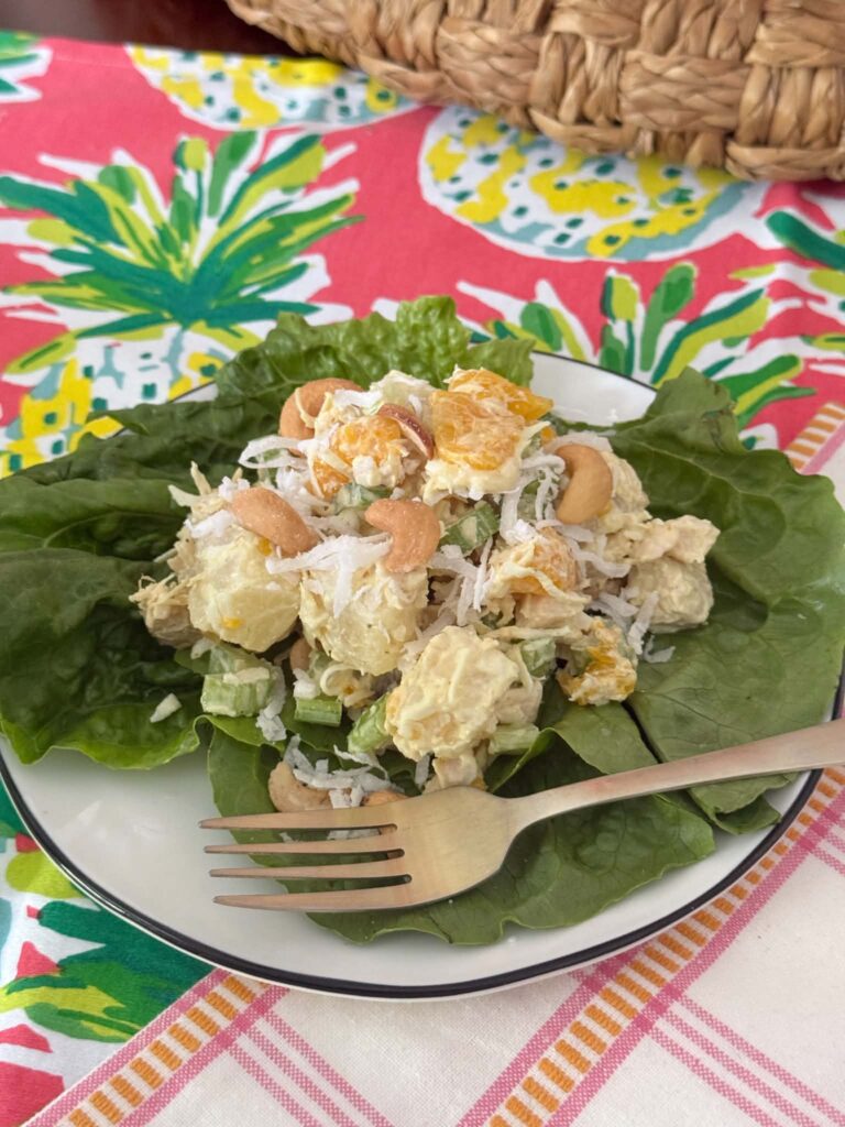 Tropical curry chicken salad on a lettuce leaf bed on a plate.