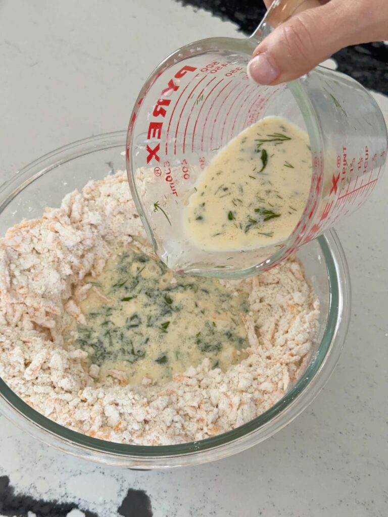 Pouring a wet mixture in the "well" of dry ingredients for savory cheese muffins.