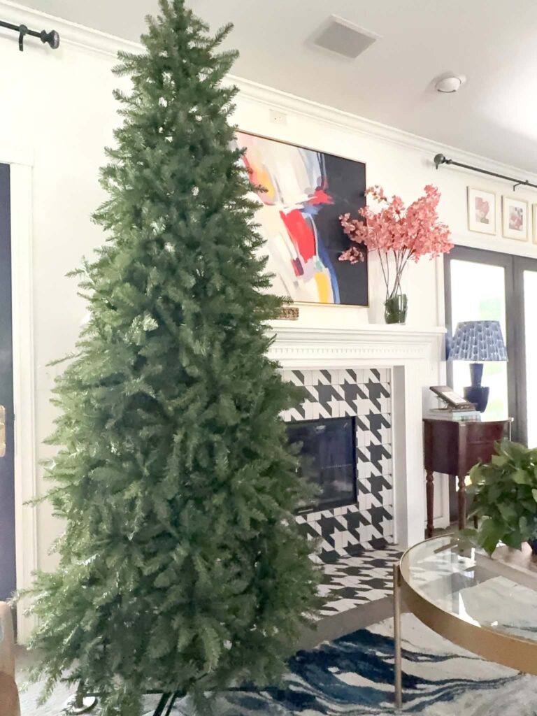 This best slim artificial Christmas tree displayed by a fireplace.