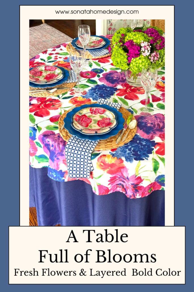 A decorated summer tablescape with fresh flowers, floral linens, geometric napkins, and glass goblets.
