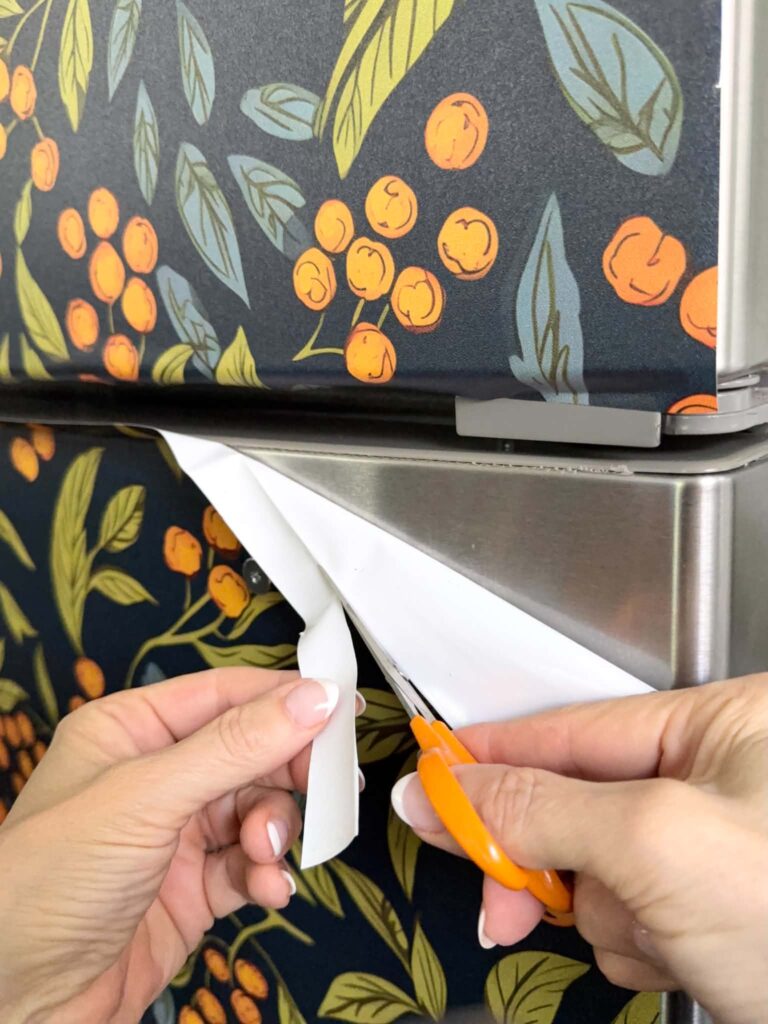 Trimming excess wallpaper from refrigerator door.