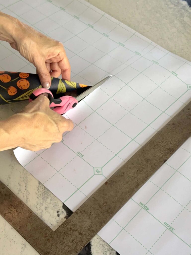Cutting peel and stick wallpaper.