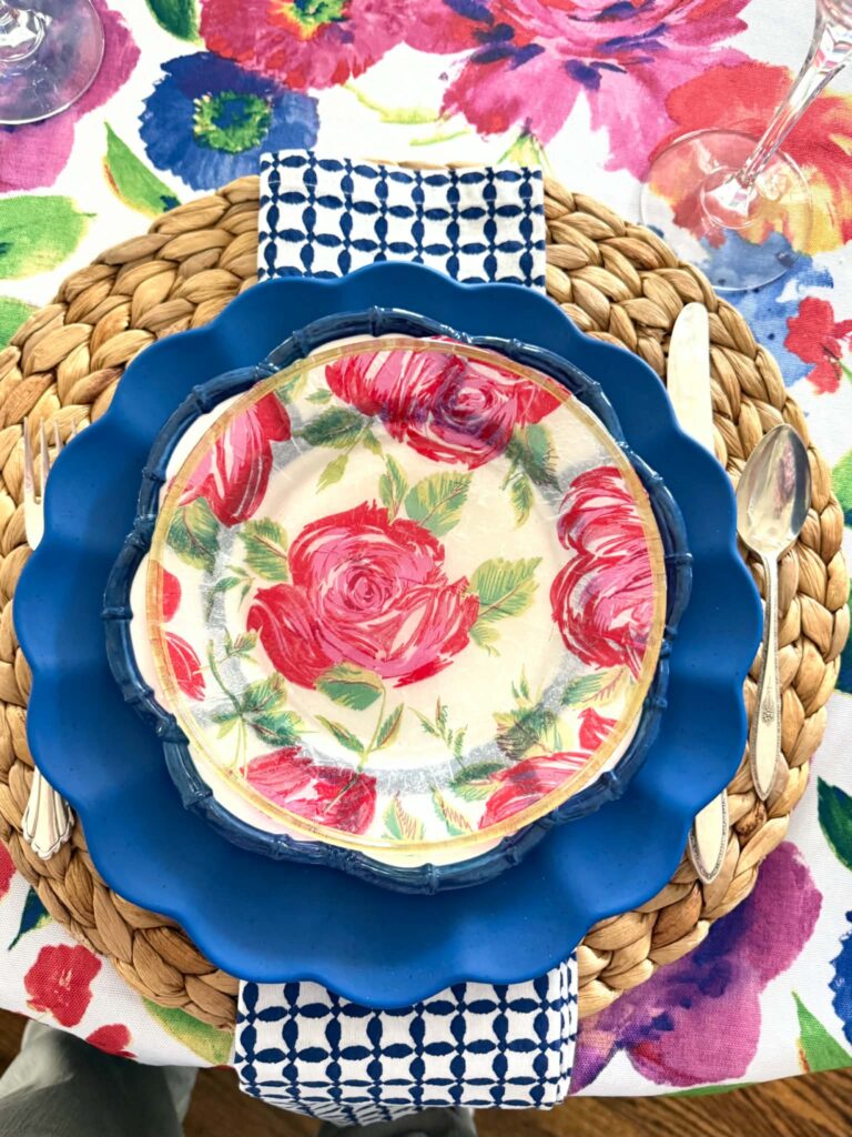 A pink floral plate layered on a blue plate.