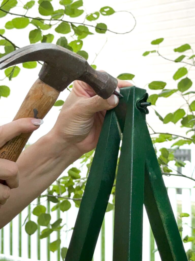 Hammering a nail into a painted wood easel.
