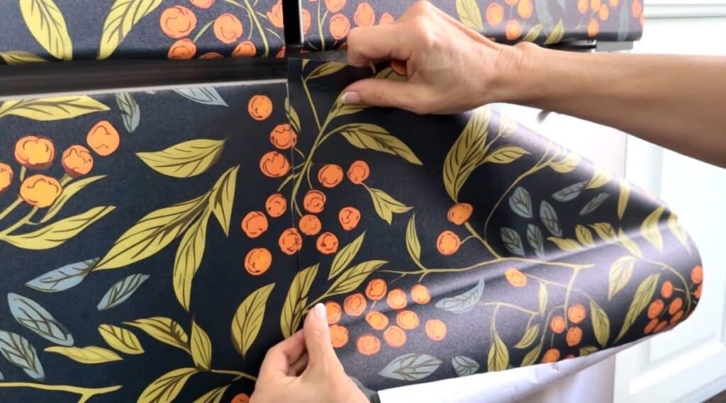 Lining up wallpaper pattern on a freezer door panel.