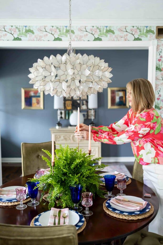 A woman lighting candles in a decorated dining room.