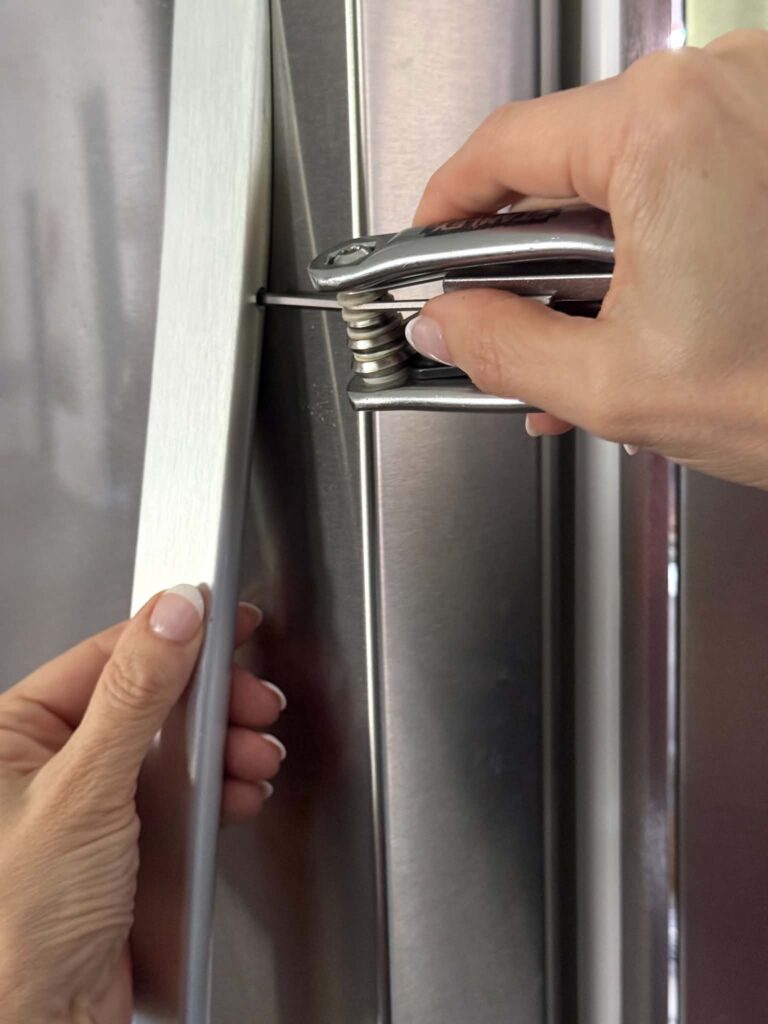 Removing a refrigerator door handle with an Allen wrench.