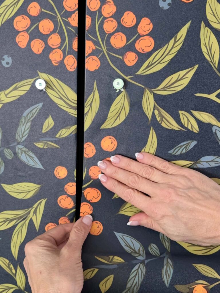Smoothing peel and stick wallpaper onto a refrigerator door.