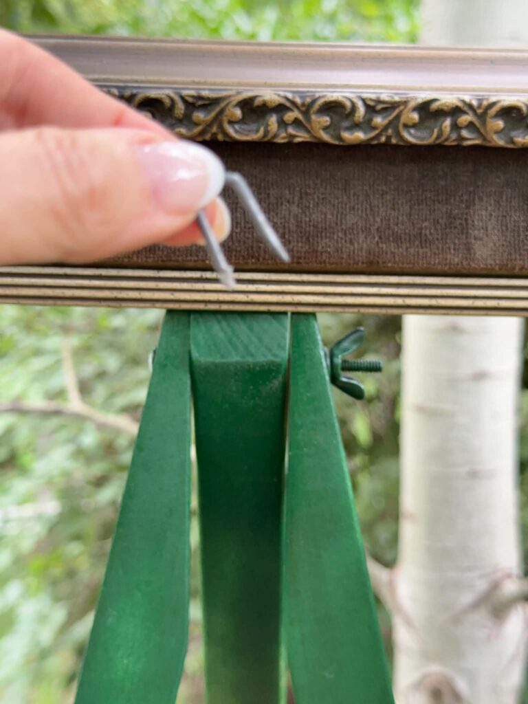 A U-nail used to repurpose an easel and old picture frame as garden art.
