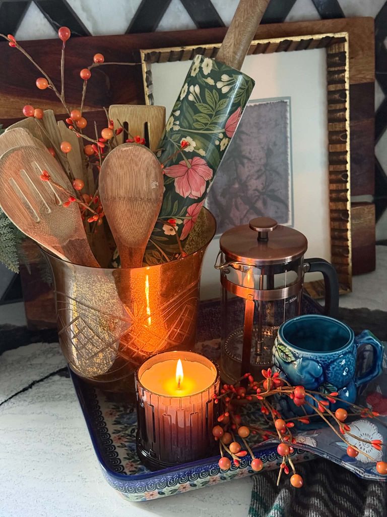 fall tray decor ideas on a ceramic tray: lighted candle, blue coffee cup, copper french press, and wooden spoons.