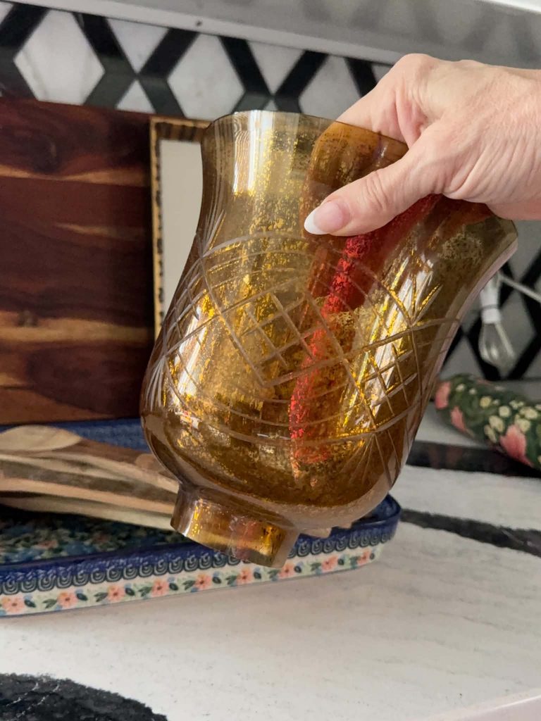 A woman's hand holding a thrifted glass light sconce.