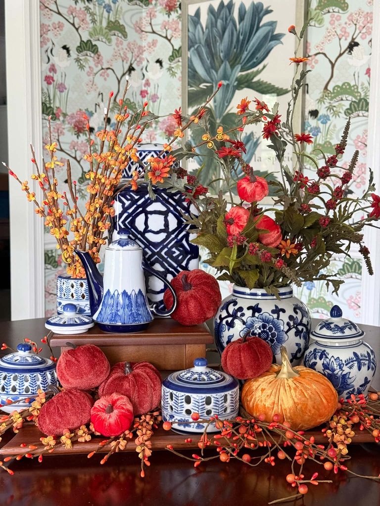 A dining room centerpiece created with layered trays, velvet pumpkins, and collected chinoiserie pieces.