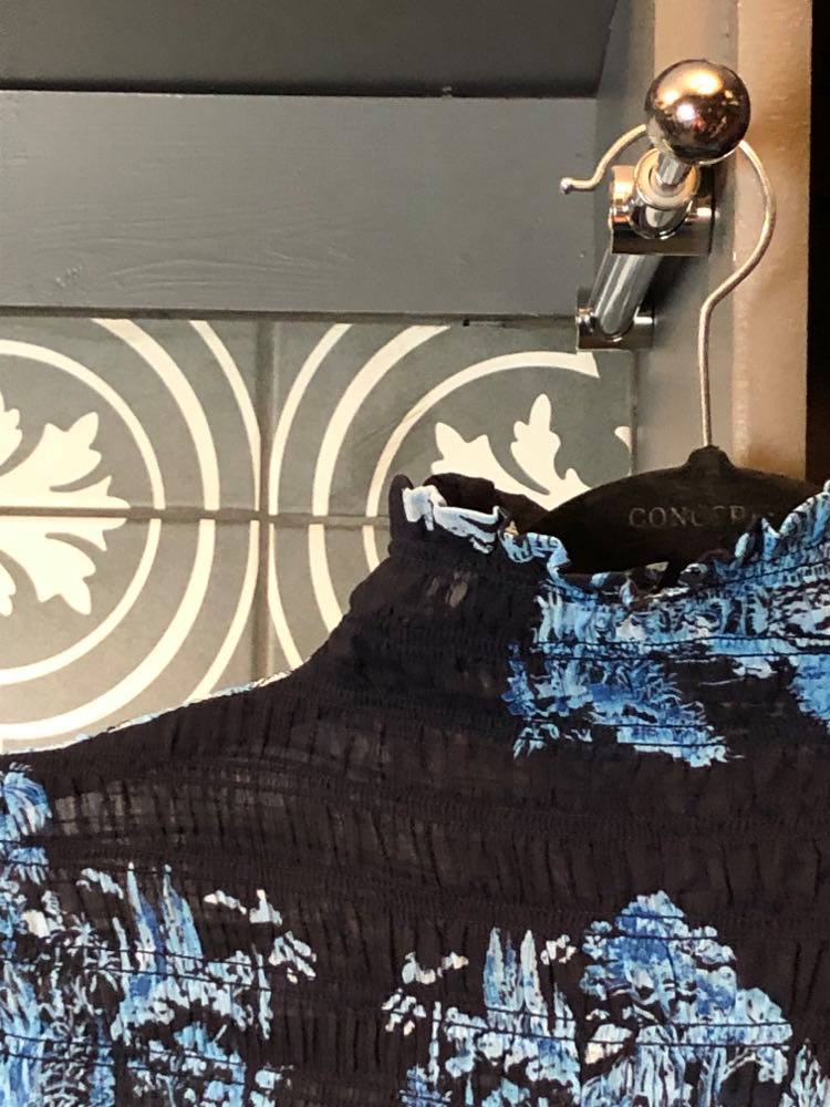 A blouse hanging from a valet rod in a small closet.