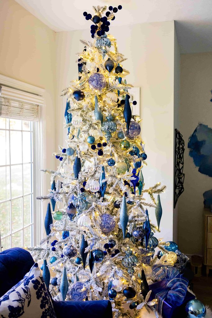 A flocked Christmas tree decorated with blue and silver ornaments.