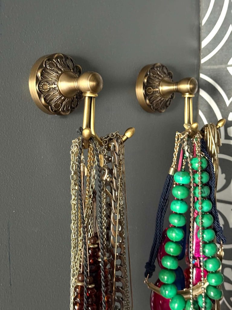 Brass hooks decorating the wall of a small closet.