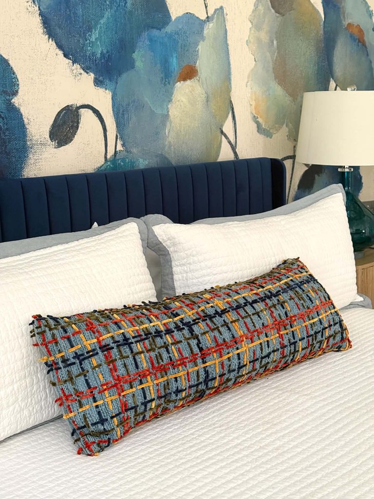 A plaid yarn pillow on a bed.