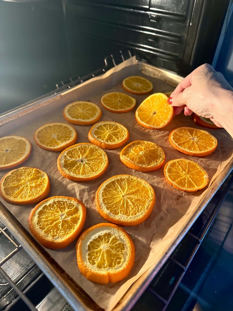 Flipping orange slices in the oven as they dry.