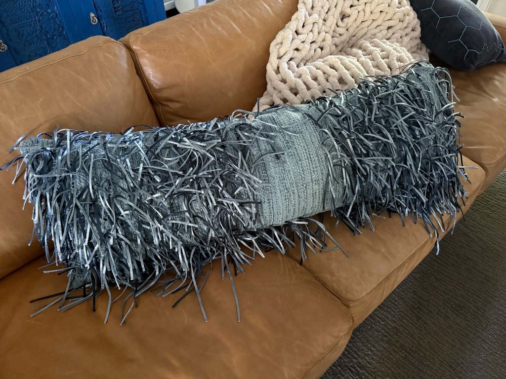A worn pillow with missing fringe.