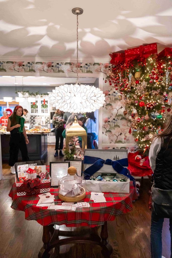 Guests milling around a Christmas tree and filling plates at a holiday buffet.
