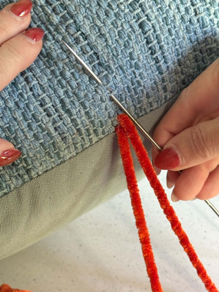 Decorating throw pillows with an upholstery needle and chenille yarn.