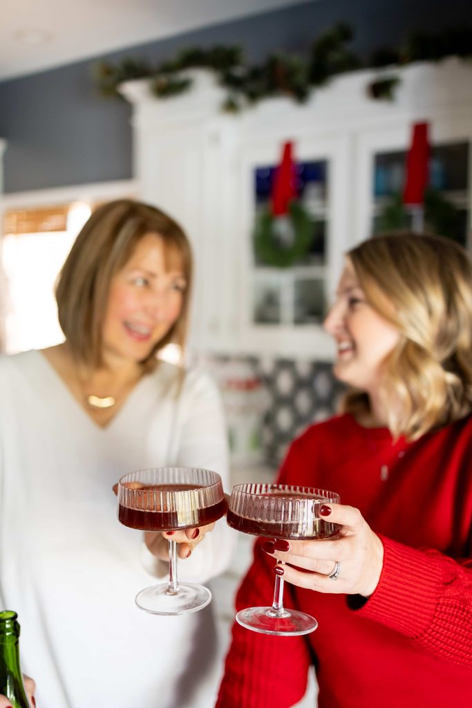 Two women clicking champagne glasses to celebrate the holidays.