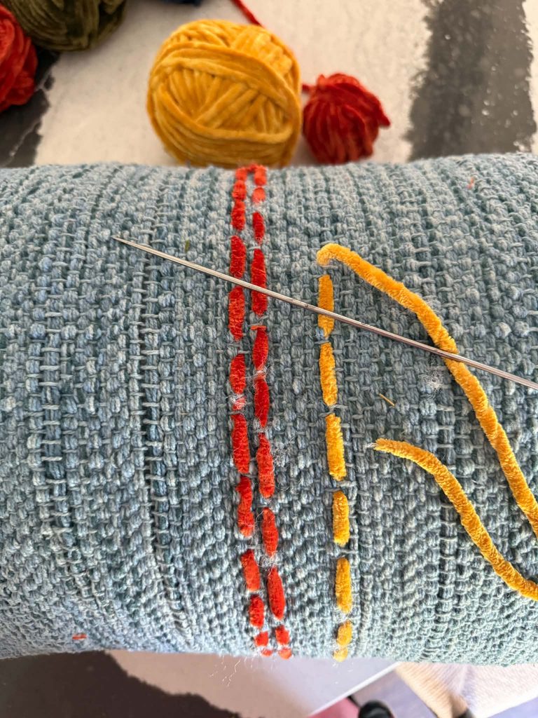 Decorating throw pillows with a running stitch of yarn.
