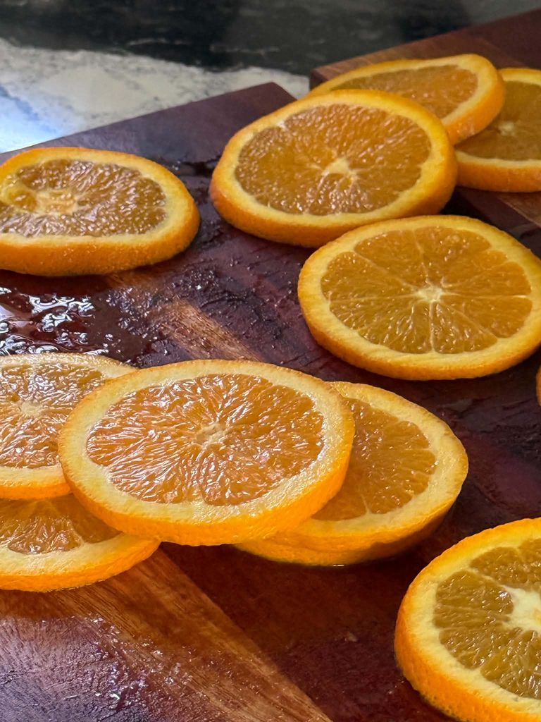 Sliced oranges on a wood cutting board.
