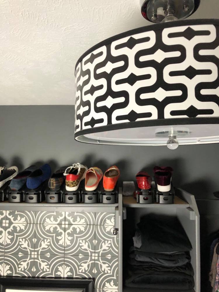 A decorative patterned lamp shade on a semi-flush lamp shade in a small walk-in closet.