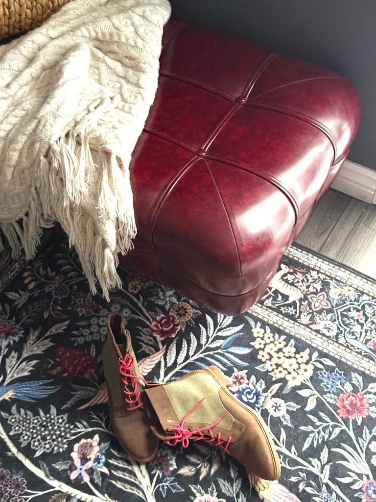 A red leather bench sitting on a rug in a small walk-in closet.